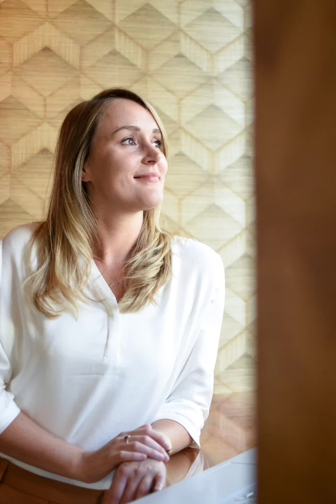 Samantha van Samantics die staat te leunen op een tafel. Ze kijkt naar buiten door een raam dat je niet in beeld ziet.