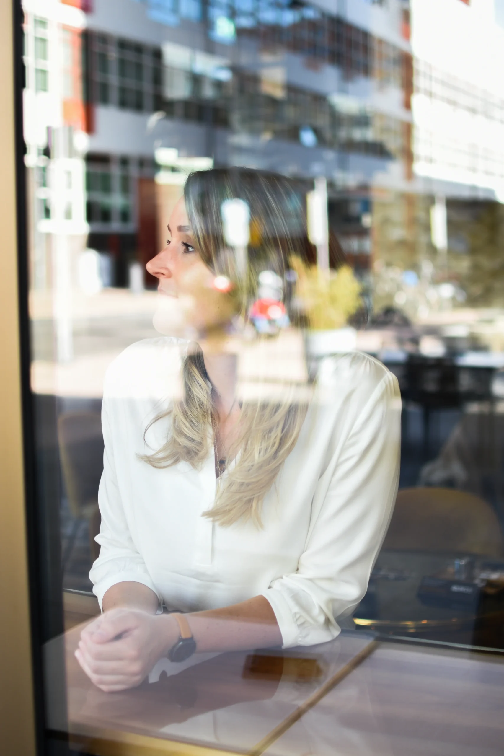 Samantha (samantics) achter een ruit, door weerspiegeling half zichtbaar.