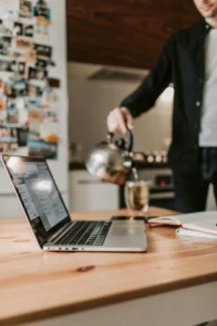Laptop op tafel met op de achtergrond een werkomgeving en iemand die pauze neemt